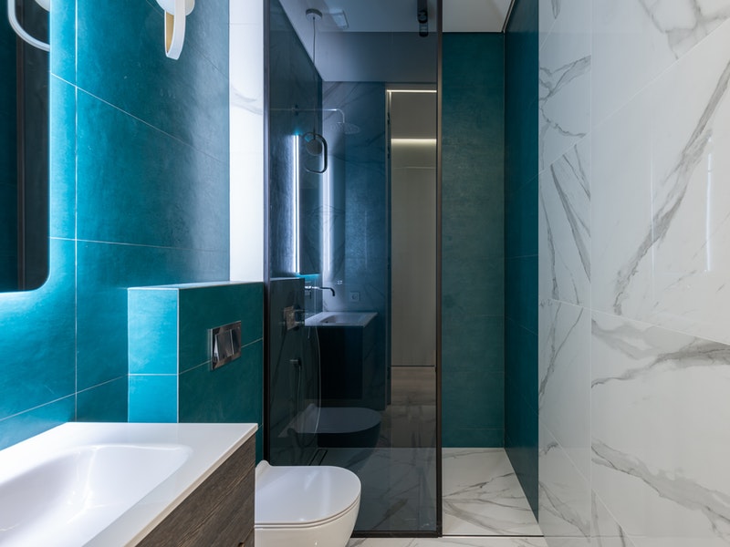 Salle de bain bleu canard, marbre blanc et douche à l'italienne